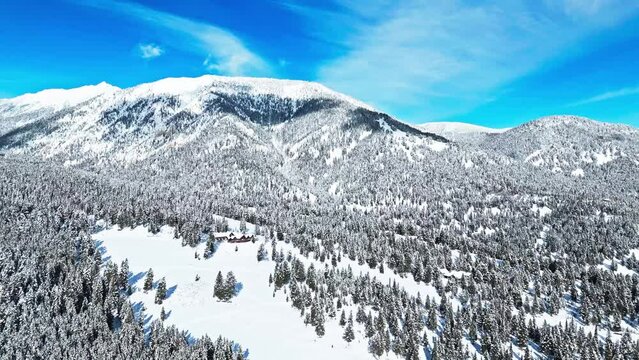 Scenic snow covered mountain forest with a house  aerial view at sunny day