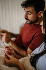 Couple absorbed in pregnancy test instructions in bed