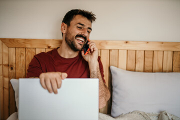 Man enjoying a lazy start while staying connected with laptop and smartphone