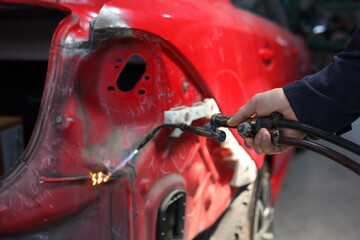 Auto mechanic working in garage. Repair service. Worker mechanics in uniform are working in auto service with lifted vehicle. Car repair maintenance.