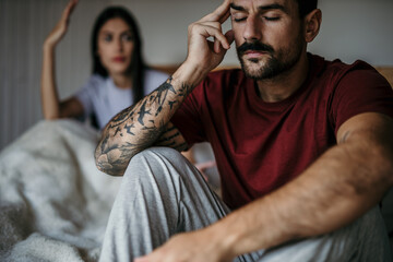 Frustrated couple in bed engaged in a morning argument