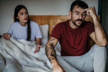 Frustrated couple in bed engaged in a morning argument