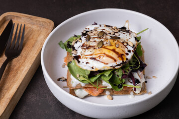 White plate of waffles and salmon with egg and seeds angle view ob dark background.
