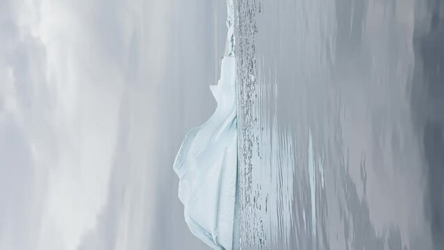 A huge high breakaway glacier is passing by in the southern ocean off the coast of Antarctica, the Antarctic Peninsula, the Southern Circle, azure water, cloudy weather
