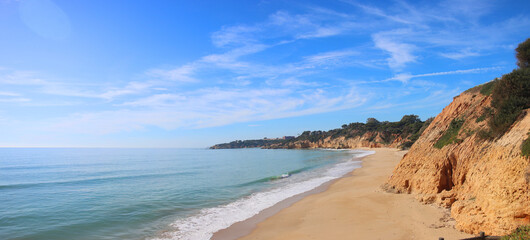 Panoramic view of lonely beach in Portugal Algarve under blue cloudy sky