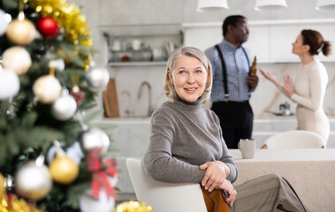 Elderly woman smiling during family quarrel between couple of adult man and woman in kitchen..