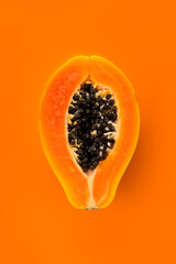 Papaya fruit on orange, yellow background. Half of fresh organic Papaya exotic fruit close up. Vertical image. Top view