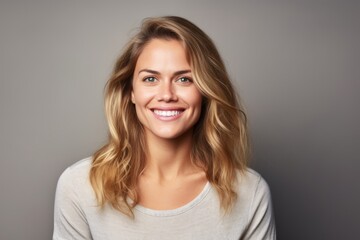 Smiling young woman with long blonde hair looking at camera. Studio shot.