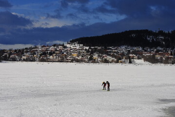Östersund, Sweden 2024.02.25 
   Park and lake in winter in the city. Winter park in Östersund. People sunbathe, barbecue, ski, and skate.

