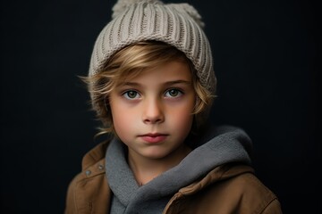 Portrait of a cute little boy in a warm hat and coat on a dark background