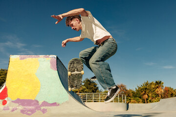 Young skateboarder flies with his board on the ramp of a skate park