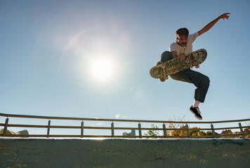 Active skateboarder jumping and performing a trick in the air in ramp of a skate park