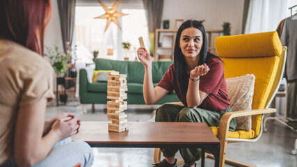 two women young females sisters friends play board game at home