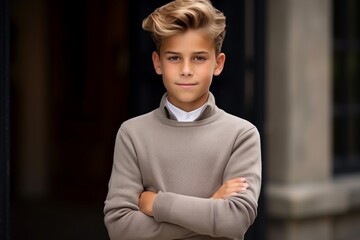 Portrait of a handsome young boy with blond hair in a sweater.