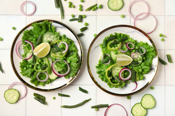 Bowls of tasty vegetable salad on white tile background