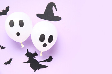 Funny Halloween white balloons and party decorations on lilac background