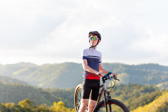 Brazilian cyclist resting beside his mountain bike atop a mountain, enjoying nature's tranquility. The image portrays the cyclist lifestyle and mountain biking enthusiasts	