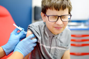A little boy is being vaccinated. A child is very afraid of the injection. Schoolkid nervous during...