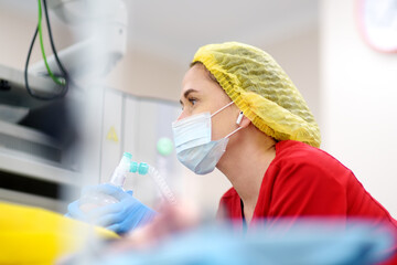 Female anesthesiologist injects anesthesia into patient face mask. General sedation while surgery operation. Paramedic putting oxygen mask for breathing and ventilation of person during resuscitation - Powered by Adobe