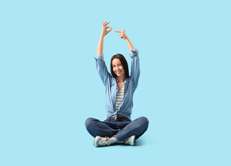 Young woman showing OK on blue background
