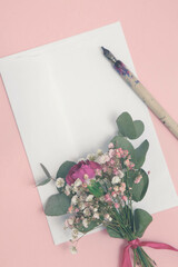 Bukiecik subtelnych kwiatków na kartce papieru i pióro do kaligrafii. 