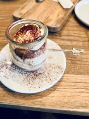 Tiramisu dessert in a glass jar on a wooden table