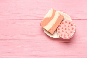 Plate with hair scalp massager and shampoo bar on pink wooden background