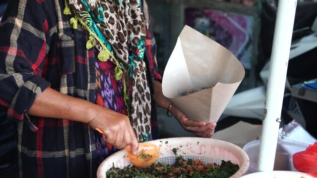 street vendor wrapping Pecel vegetables at the market