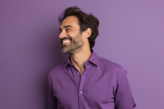 Portrait of a handsome young man laughing and looking away over purple background