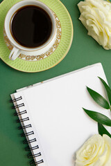 Notes na biurku, róże i kawa, na zielonym tle. 