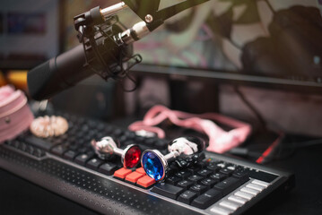 Metal anal plugs on a webcam model streamer table with female pink panties and studio microphone. Online video sex concept. - obrazy, fototapety, plakaty