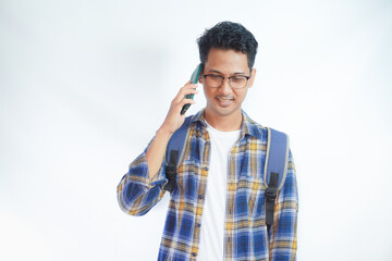 Cheerful young Asian student man wearing casual clothes with backpacks holding school books and Talking on mobile phone isolated on white background. Education in high school university college concep