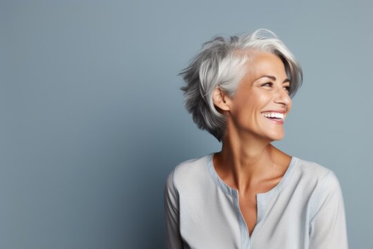 Portrait of a happy senior woman with grey hair, over grey background