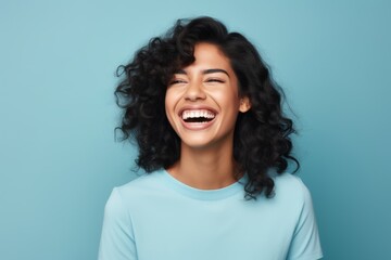 Portrait of happy young asian woman laughing and looking at camera over blue background