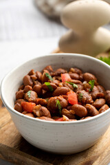 Food dish made of beans, tomatoes, and cilantro on a wooden table