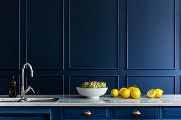 Modern navy blue kitchen interior with marble countertop, stainless steel faucet, and fresh lemons providing copy space on the left side
