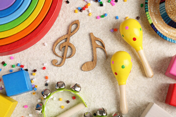 Baby song concept. Wooden notes, kids musical instruments and toys on beige carpet, flat lay