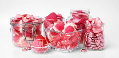 Different yummy pink candies in glass jars and bowls on white background. Banner design
