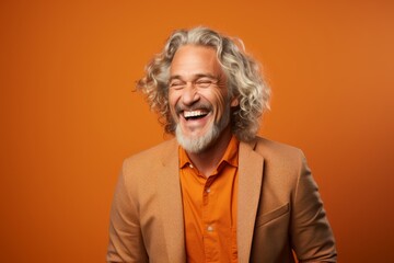 happy senior man laughing and looking at camera on orange background, empty space