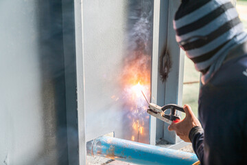 Obraz premium A metal welder welds metal a wall in a warehouse.
