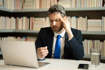 Stressed man with headache. Tired businessman is working overtime and has headache. Man with laptop...