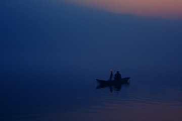 Fototapeta na wymiar Solitary Boatman on a Misty Lake at Twilight