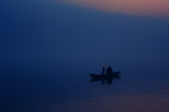 Solitary Boatman on a Misty Lake at Twilight