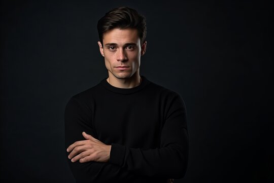 Portrait of a handsome young man in a black sweater on a dark background