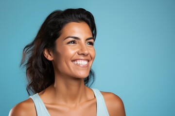 Portrait of a beautiful smiling young woman, isolated on blue background