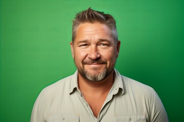 Portrait of a happy mature man looking at camera over green background