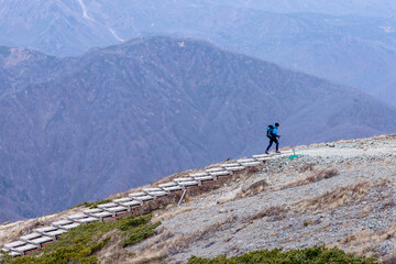 Hakuba, Japan - 4 November 2023 :  A lone hiker walking on a wooden boardwalk on a moutain during autumn at Hakuba, Japan.