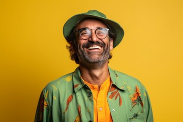 Cheerful man wearing a hat and glasses laughing on a yellow background