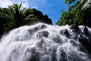Close up of Kepirohi Waterfall with water cascading over rocks on the tropical island of Pohnpei in Federated States of Micronesia - obrazy, fototapety, plakaty