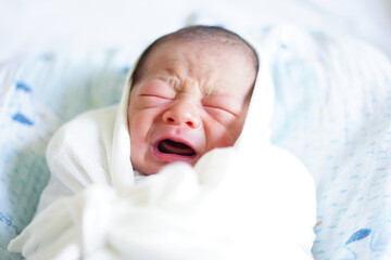 お包みに包まれて泣いている新生児 / Newborn crying in a swaddling clothes